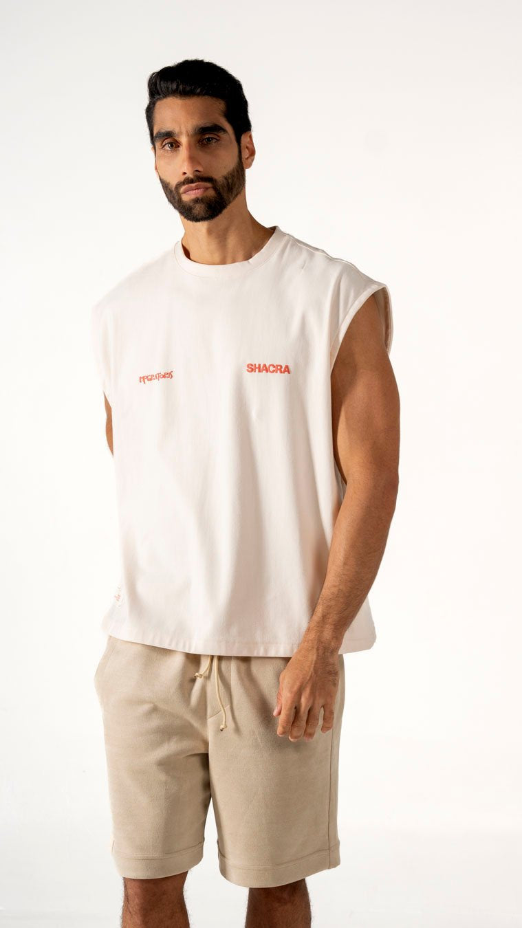 Modern male model wearing casual streetwear with sleeveless white T-shirt and beige shorts, highlighting comfortable fashion essentials from Shacra.