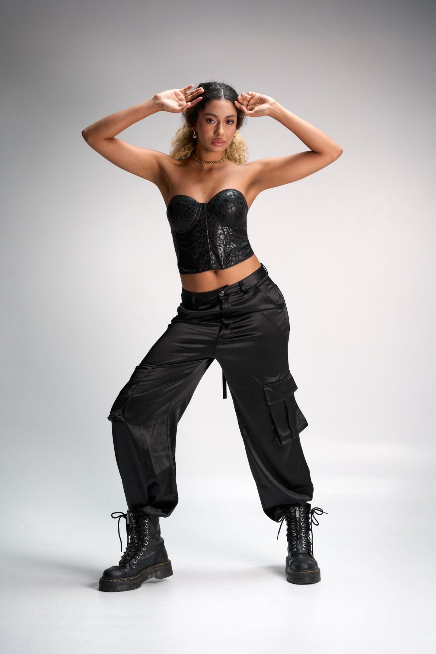 Leather corset top, black cargo pants, combat boots, edgy street style fashion, modern urban look, Shacra fashion photography, women's trendy clothing, bold style statement.
