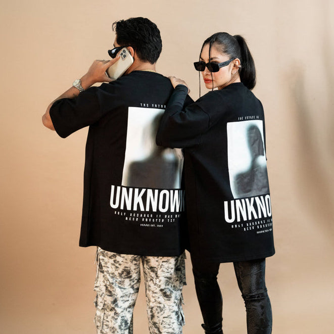 Modern streetwear fashion featuring stylish adults in matching "UNKNOWN" graphic t-shirts,paired with trendy accessories like sunglasses and statement jewelry, showcasing contemporary urban style.