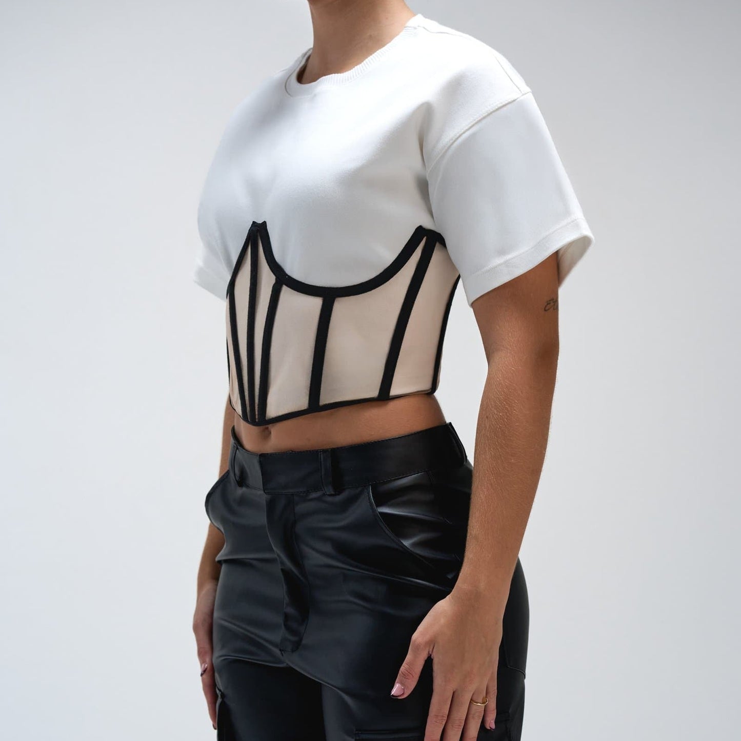 Modern black leather cargo pants with stylish design and multiple pockets, paired with a unique cropped white T-shirt with black piping accents for trendy streetwear fashion.
