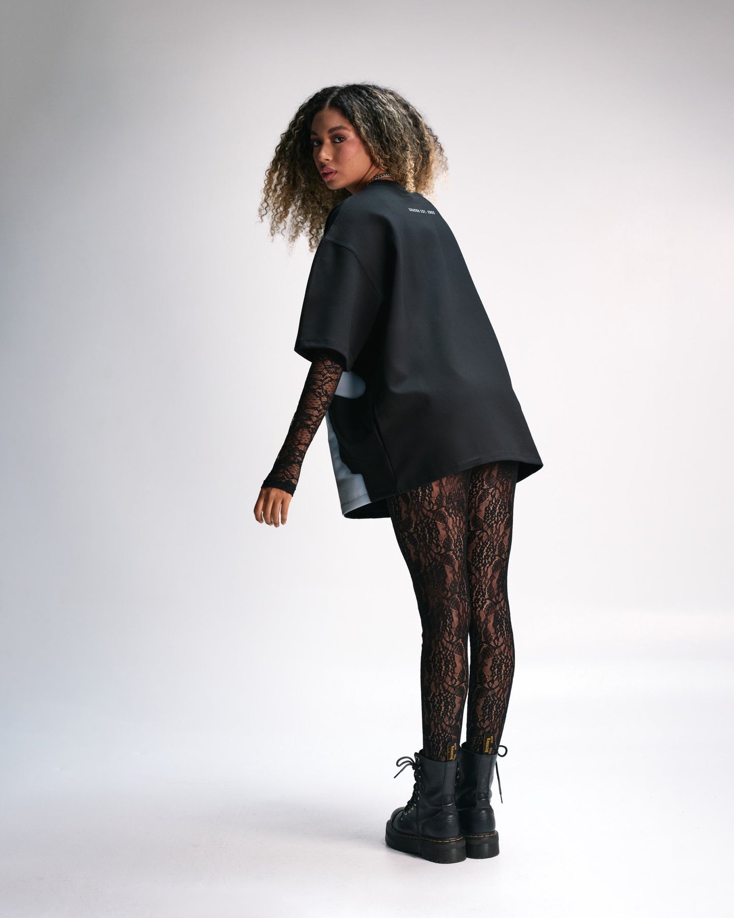 Black oversized t-shirt with lace sleeves paired with black lace leggings and combat boots, showcasing edgy, fashion-forward streetwear style. Perfect for modern, urban fashion statements emphasizing individuality.