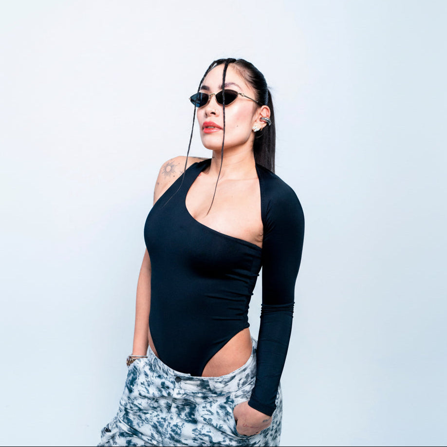 Chic woman wearing stylish sunglasses, black bodysuit, and trendy tie-dye pants, showcasing modern fashion and confident attitude. Perfect for fashion-forward looks and urban style inspiration.