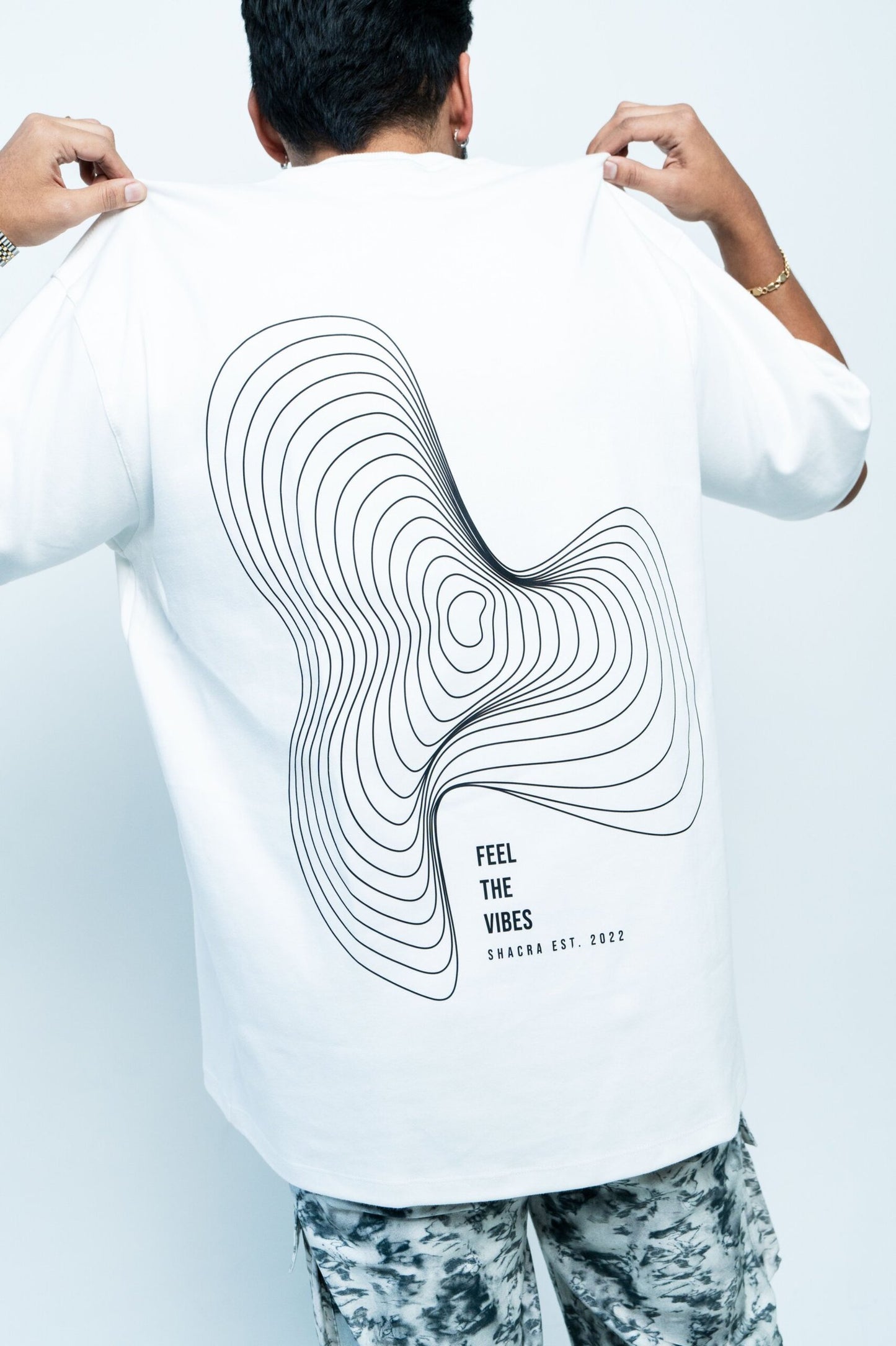 Contour line design on a white T-shirt with text "Feel the Vibes" by Shacra, highlighting contemporary fashion and stylish graphic apparel.
