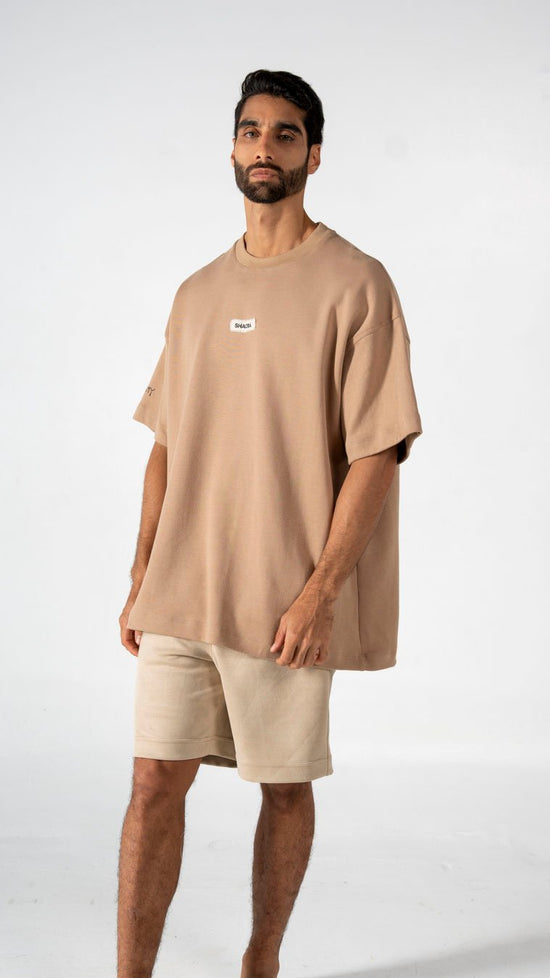 Relaxed beige oversized t-shirt with "SHACRA" branding, paired with matching beige shorts for a casual, modern summer look. Perfect for effortless streetwear style.