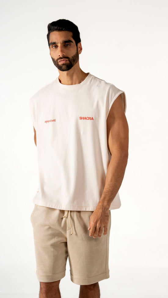 Modern male model wearing casual streetwear with sleeveless white T-shirt and beige shorts, highlighting comfortable fashion essentials from Shacra.