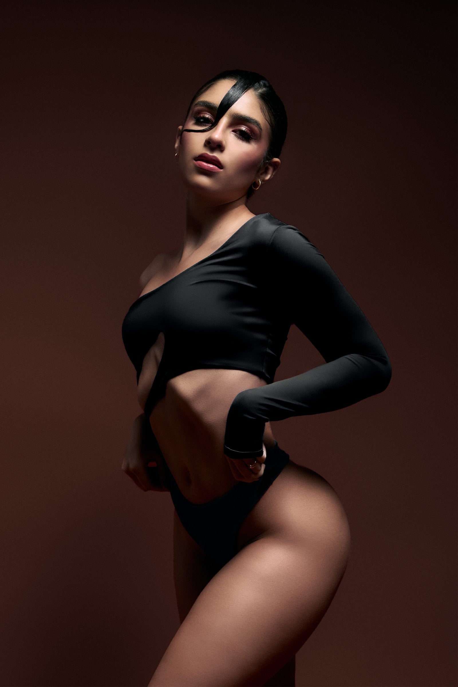 Elegant model in black edgy fashion on dark gradient background, showcasing modern glamour, confidence, and sophisticated style for fashion photography and beauty branding.