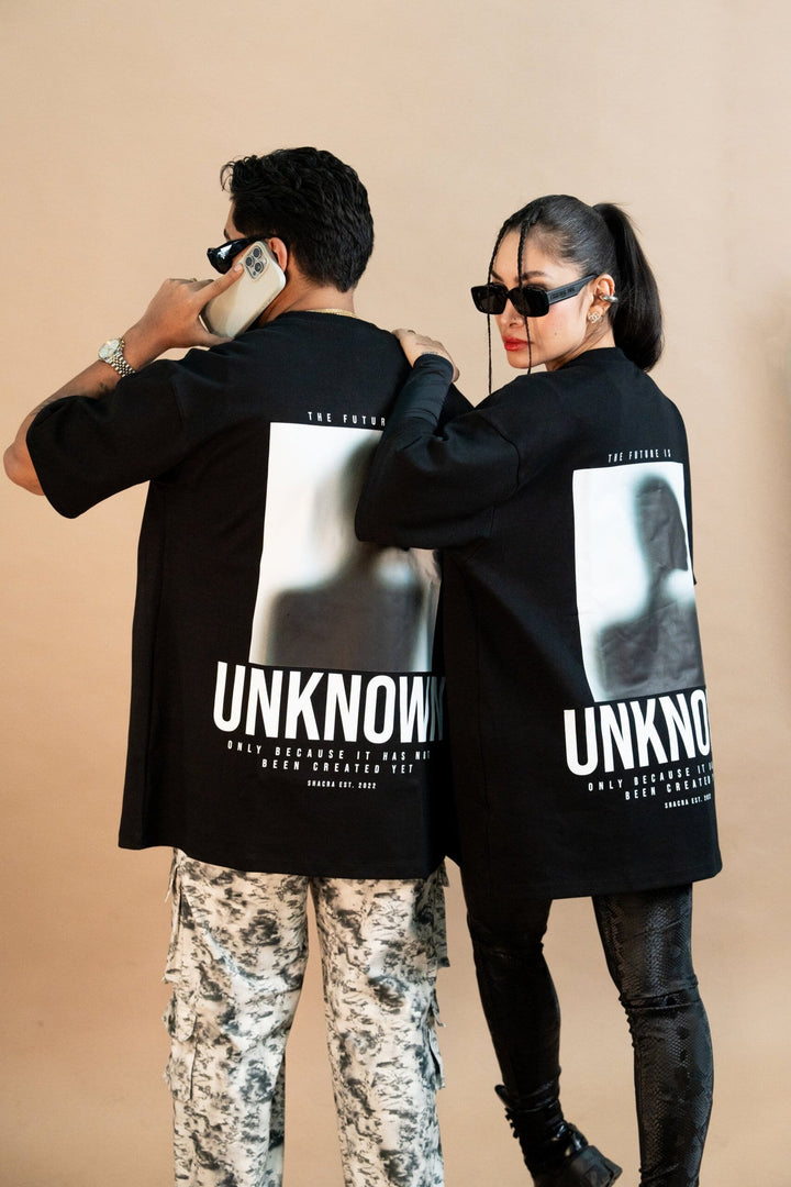 Modern streetwear fashion featuring stylish adults in matching "UNKNOWN" graphic t-shirts,paired with trendy accessories like sunglasses and statement jewelry, showcasing contemporary urban style.