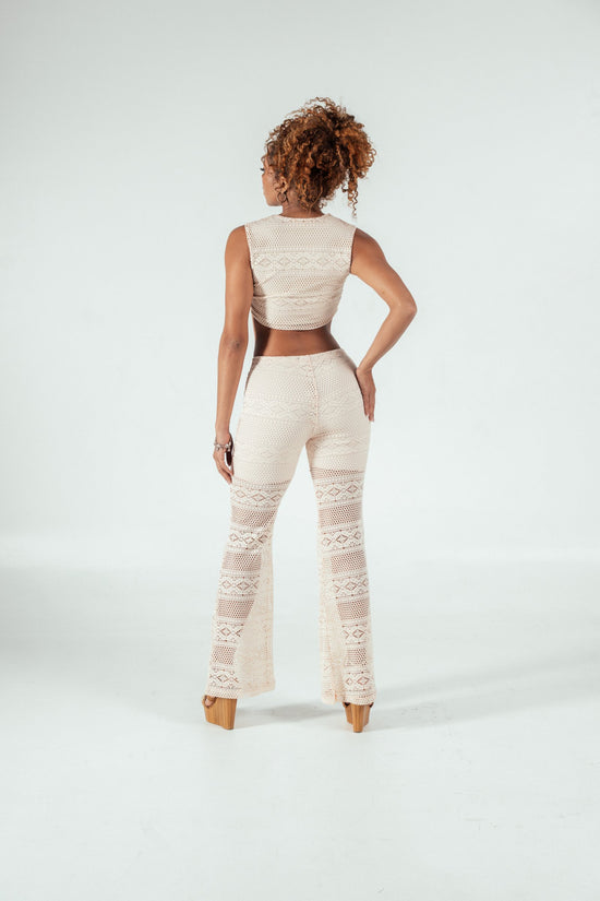 Elegant woman modeling crocheted cream-colored lace outfit, back view, showcasing stylish boho-chic fashion, perfect for summer wear or beach vacations, on a plain white background.