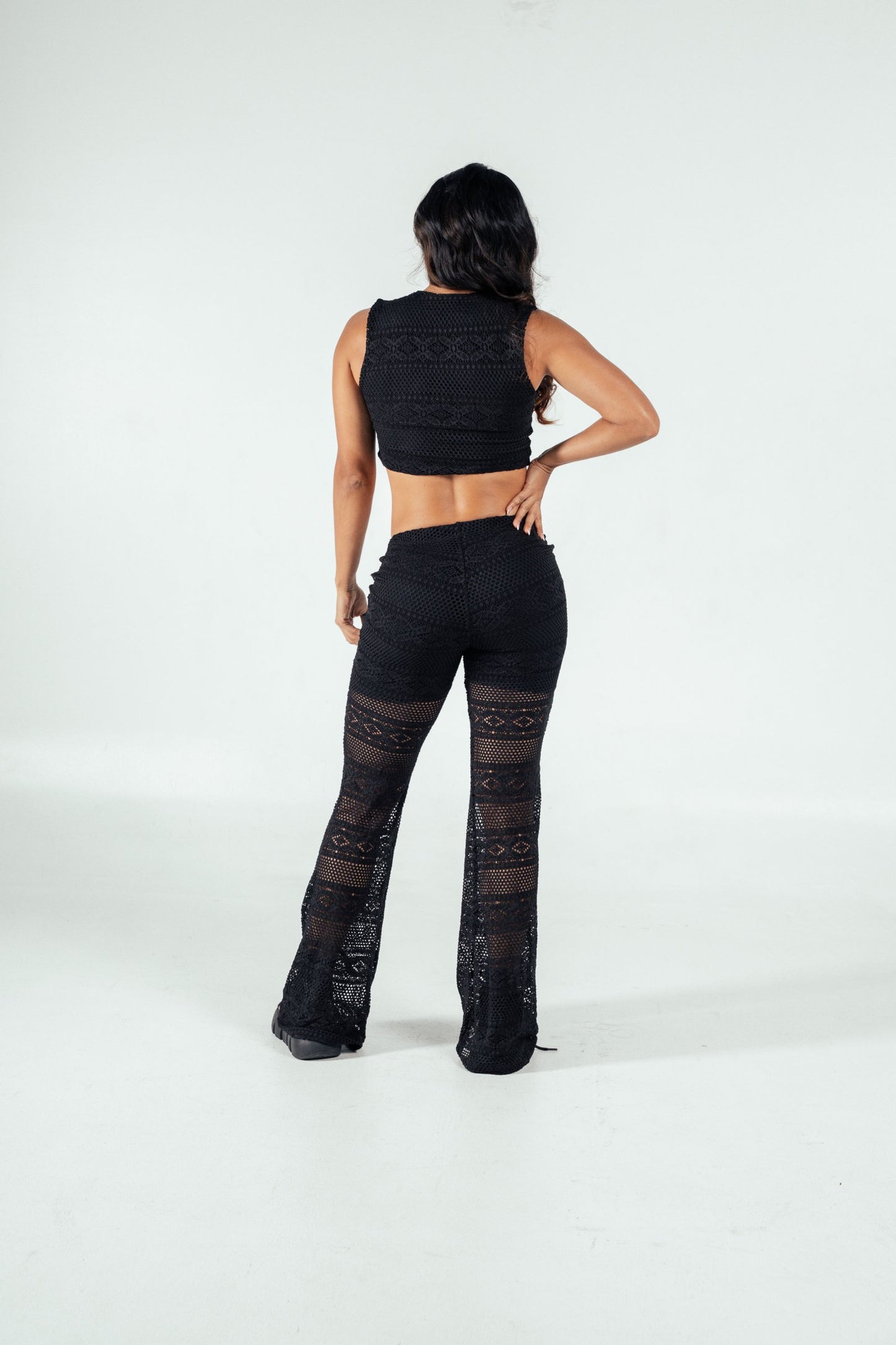 Black lace crochet two-piece outfit featuring a sleeveless crop top and wide-leg pants, perfect for trendy, stylish summer or beachwear looks.