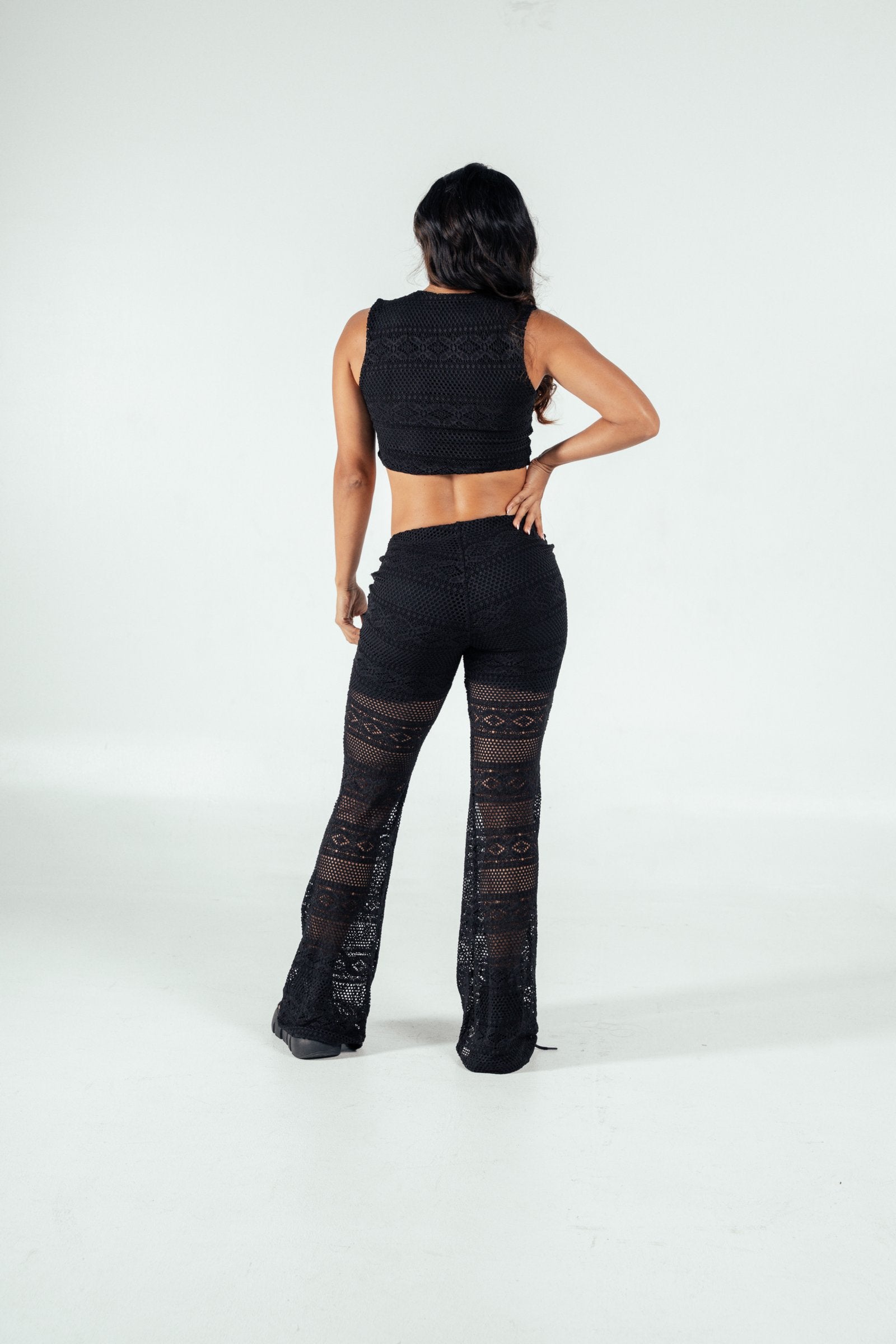 Black lace crochet two-piece outfit featuring a sleeveless crop top and wide-leg pants, perfect for trendy, stylish summer or beachwear looks.