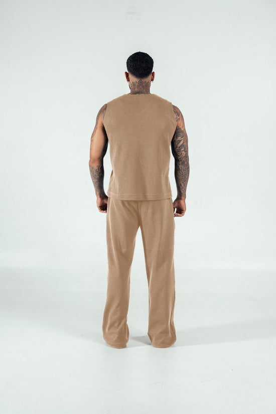 Comfy beige loungewear set on a tattooed man, casual home clothing for relaxed style, cozy lounge outfit, minimalist comfortable outfit for men, stylish loungewear for men.