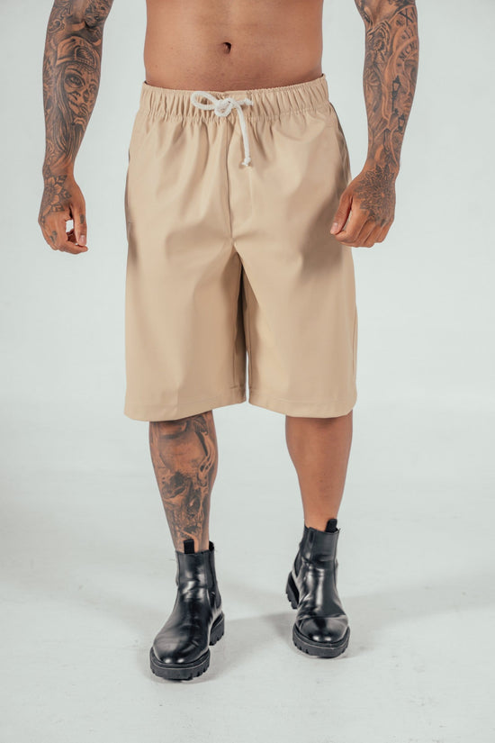 Beige men's casual shorts with drawstring, combat boots, tattooed male model, streetwear fashion, summer clothing, edgy style, men's fashion accessories, stylish streetwear, trendy menswear.