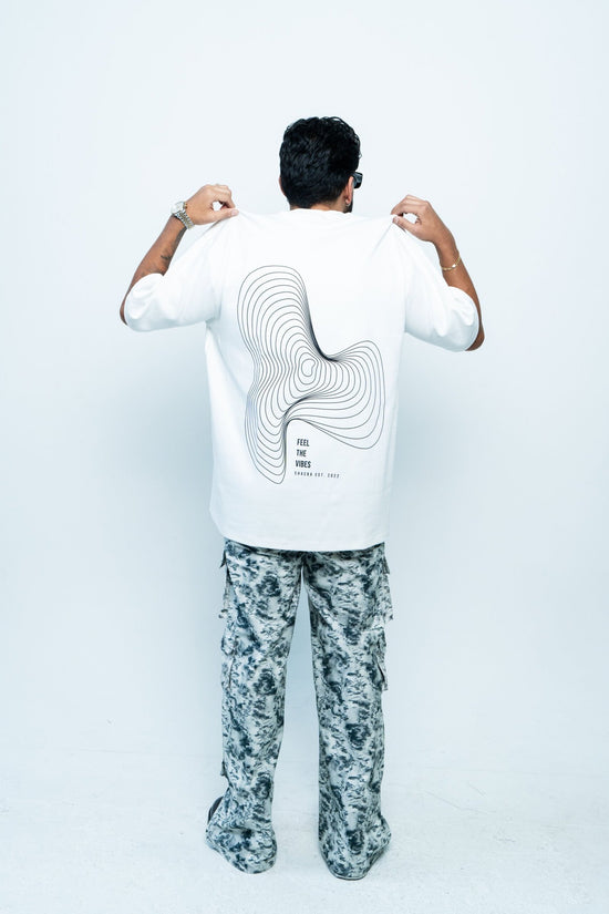 Modern man wearing graphic t-shirt from Shacra brand showcasing contemporary fashion and stylish casual wear, standing against a plain white background, highlighting the apparel design and aesthetic appeal.
