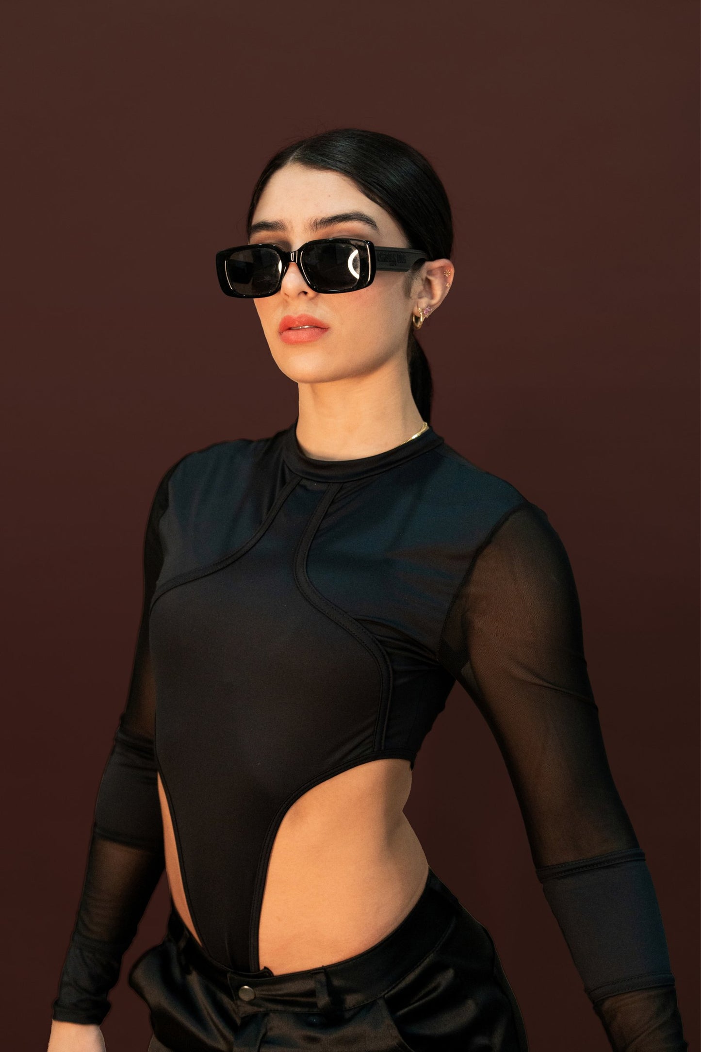 Black sporty fashion model wearing stylish sunglasses and a sleek black cut-out top, showcasing modern streetwear and fashion accessories for an edgy, contemporary look.