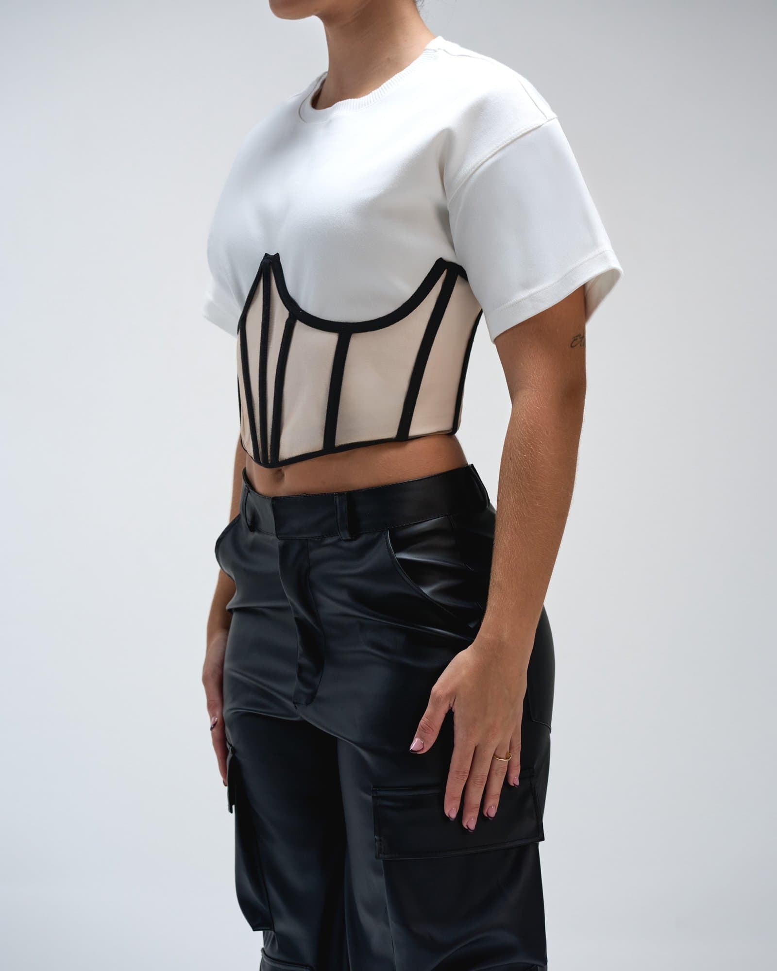 Modern black leather cargo pants with stylish design and multiple pockets, paired with a unique cropped white T-shirt with black piping accents for trendy streetwear fashion.