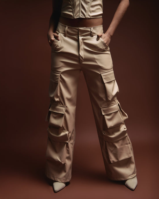 High-waisted beige cargo pants with multiple pockets, styled for a modern fashion look. Perfect for streetwear and casual outfits, showcasing trendy and versatile clothing by Shacra.