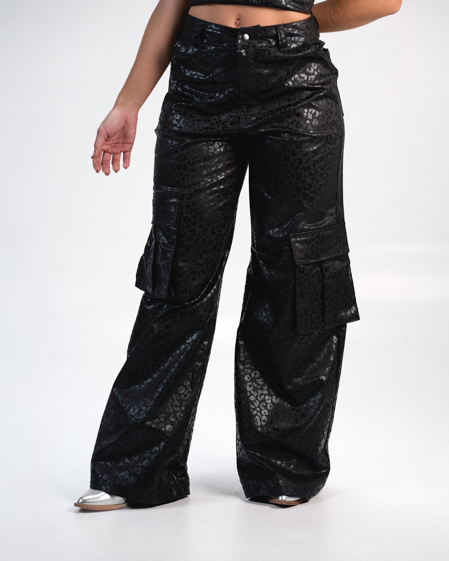 Glossy black leopard print cargo pants with wide legs, large side pockets, and a high waist, styled for a trendy, edgy look. Perfect for streetwear fashion and making a bold style statement.