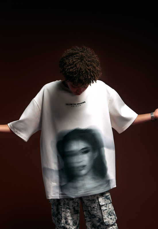 Unique streetwear featuring a printed graphic t-shirt with bold art and the phrase "Follow the Unknown" on a dark background.