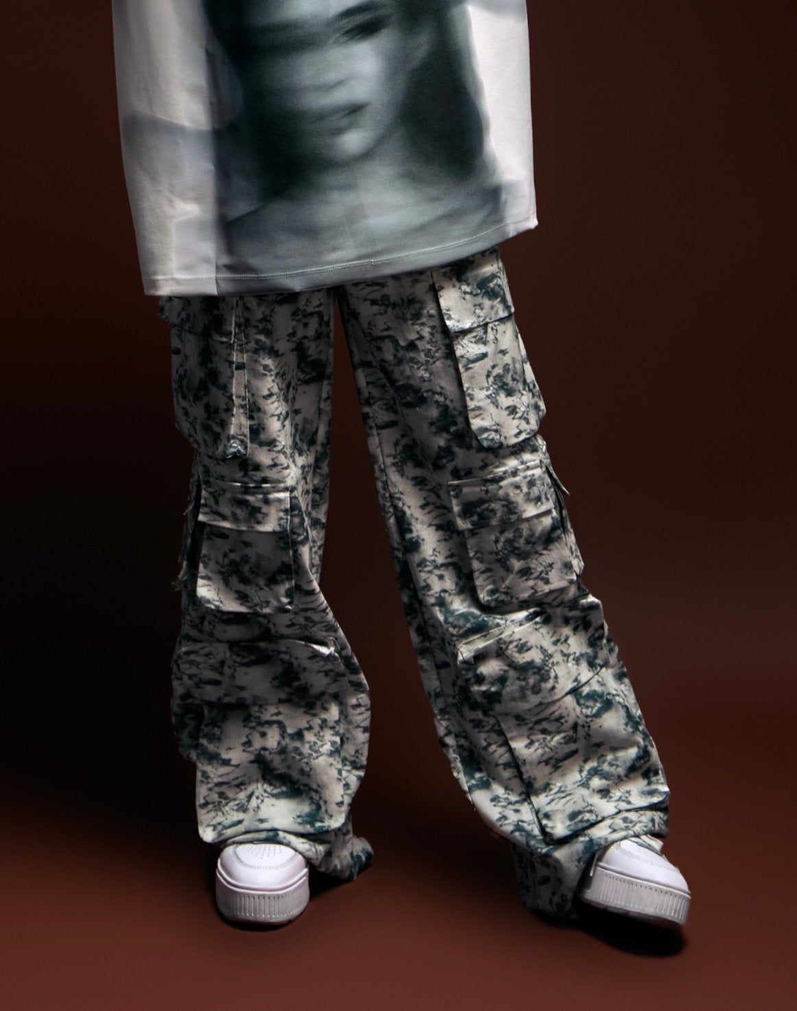 Cargo pants with a black and white camouflage pattern and chunky white sneakers, styled for a streetwear look.