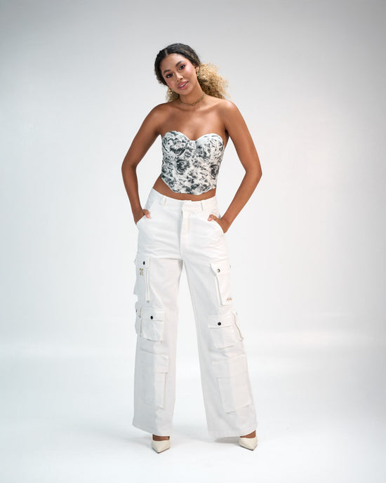 Elegant woman modeling trendy streetwear fashion with a stylish printed crop top and white cargo pants, highlighting contemporary fashion and confident style for a modern aesthetic.