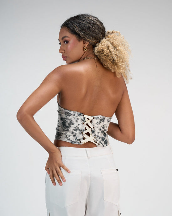 Elegant back view of a woman wearing a trendy tie-dye bustier top with lace-up detailing, paired with white high-waisted jeans, showcasing stylish summer fashion for women.