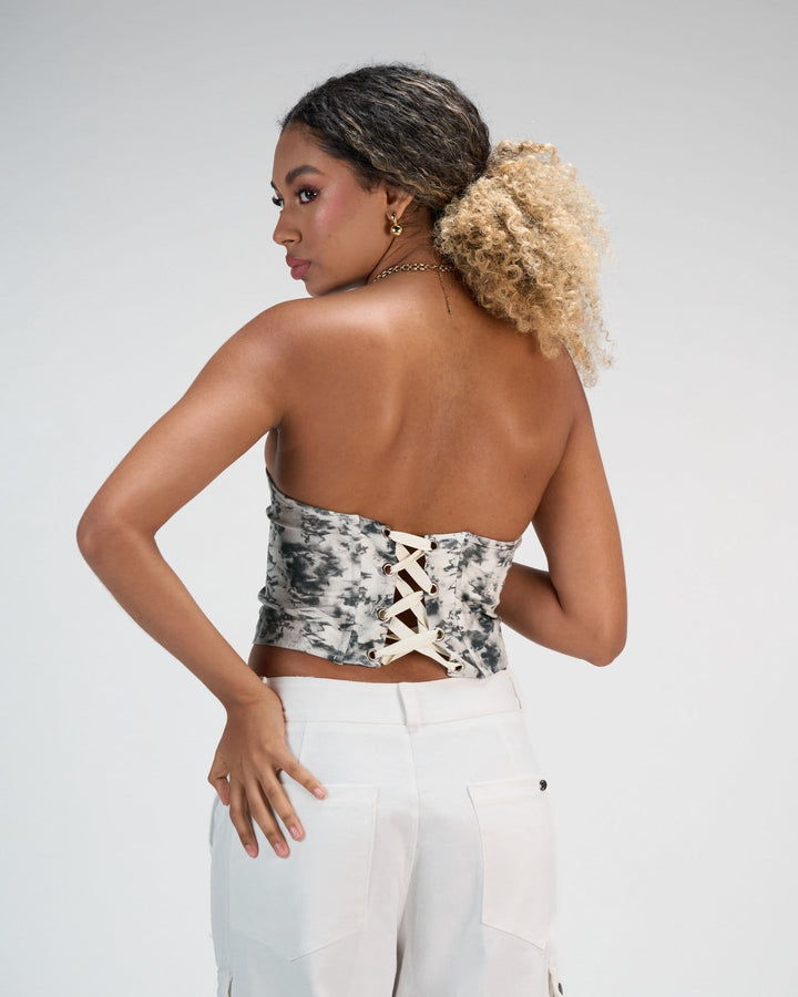 Elegant back view of a woman wearing a trendy tie-dye bustier top with lace-up detailing, paired with white high-waisted jeans, showcasing stylish summer fashion for women.