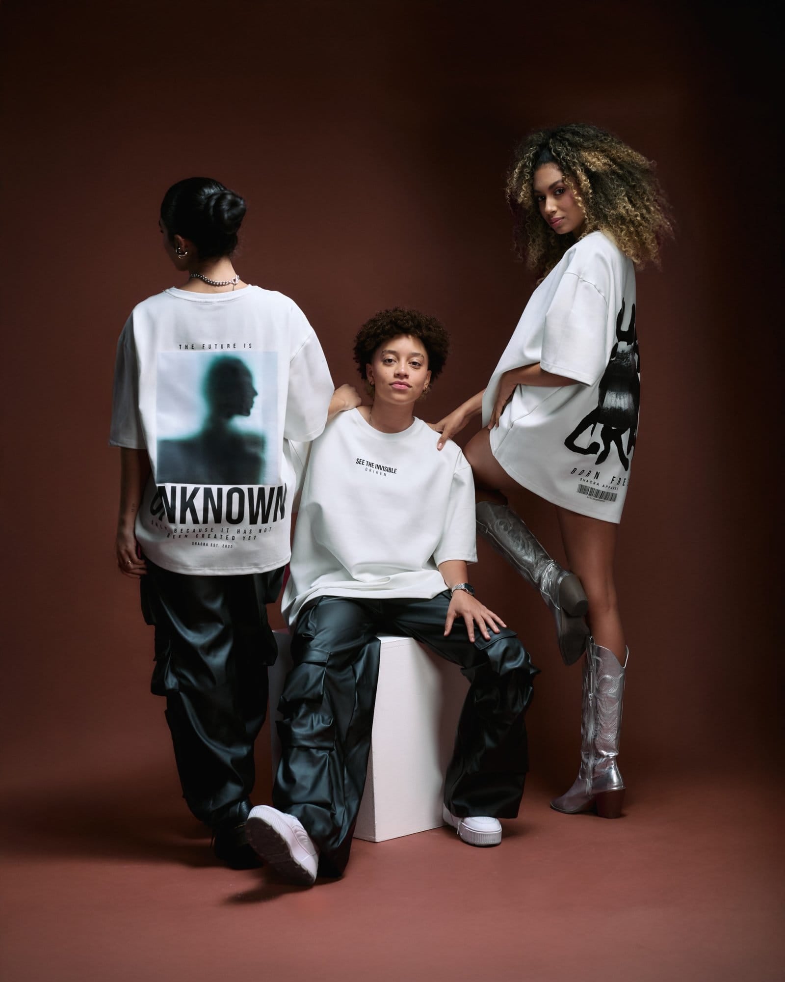 Bold women modeling streetwear and graphic tees for fashion-focused brand Shacra, showcasing trendy, edgy styles with artistic prints, perfect for modern urban fashion.