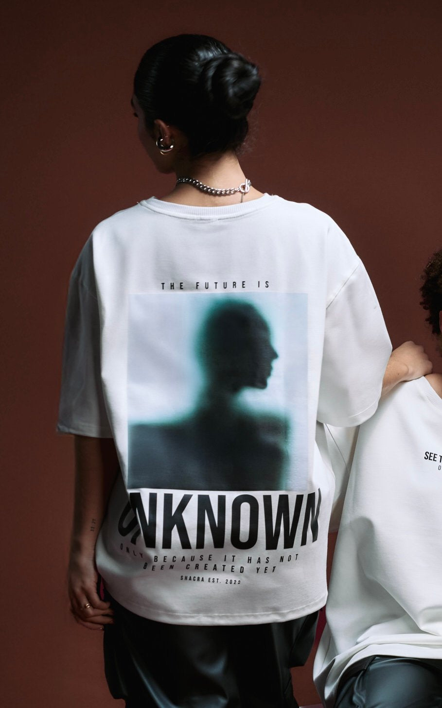 Abstract image of a woman wearing a white graphic t-shirt with modern art and philosophical text, emphasizing contemporary streetwear fashion and artistic photography.