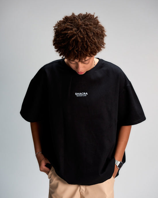Bold Black T-shirt with "SHACRA Spread Love" logo, casual streetwear style featuring relaxed fit, short sleeves, and minimalistic design. Perfect for modern fashion statements and everyday comfort.