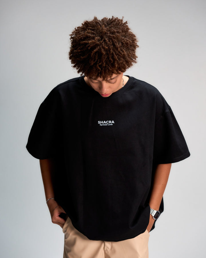 Bold Black T-shirt with "SHACRA Spread Love" logo, casual streetwear style featuring relaxed fit, short sleeves, and minimalistic design. Perfect for modern fashion statements and everyday comfort.