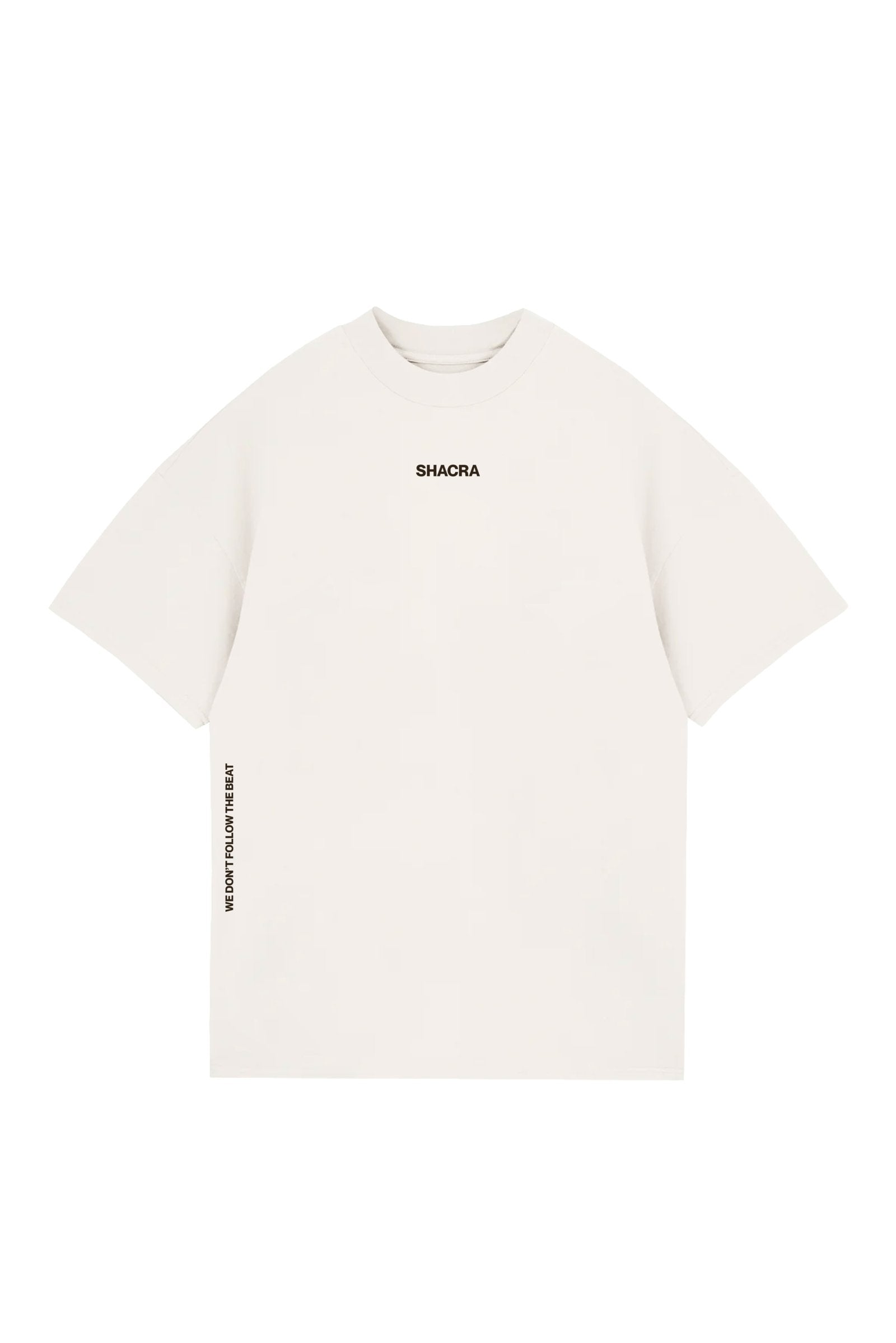 White oversized T-shirt with black branding "SHACRA" on the chest and side text "WE DON'T FOLLOW THE BEAT" printed vertically on the left sleeve, designed for streetwear fashion.