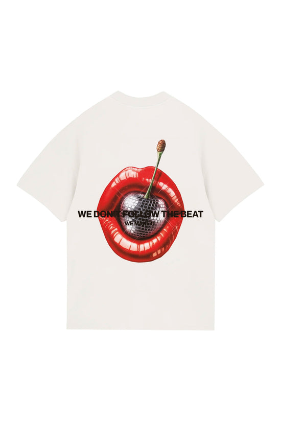 Bright white T-shirt featuring bold graphic design of glossy red lips with a cherry and disco ball center, accompanied by the phrase "WE DON'T FOLLOW THE BEAT" for a trendy, edgy look.