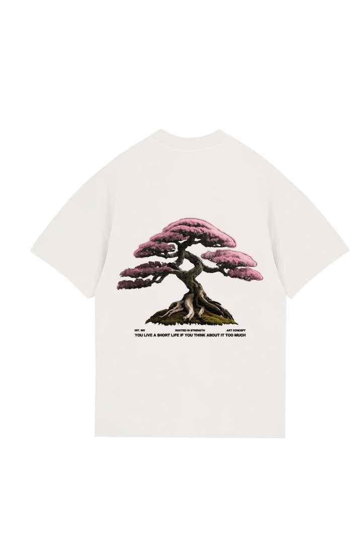 Vibrant pink bonsai tree illustration on a white T-shirt, representing strength and mindfulness, with inspirational quote emphasizing the importance of positive thinking in life.