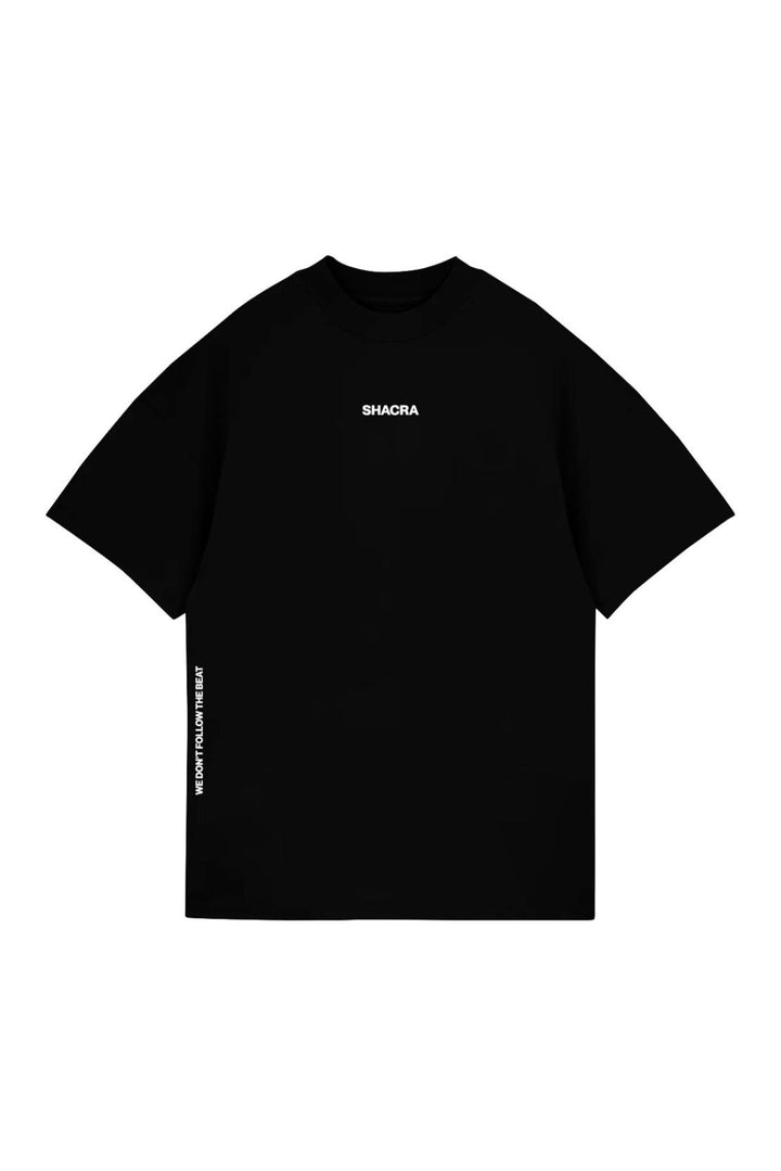 Vintage black T-shirt with "SHACRA" logo and "WE DON'T FOLLOW THE BEAT" slogan in white text, streetwear style, casual graphic tee for fashion-forward individuals.